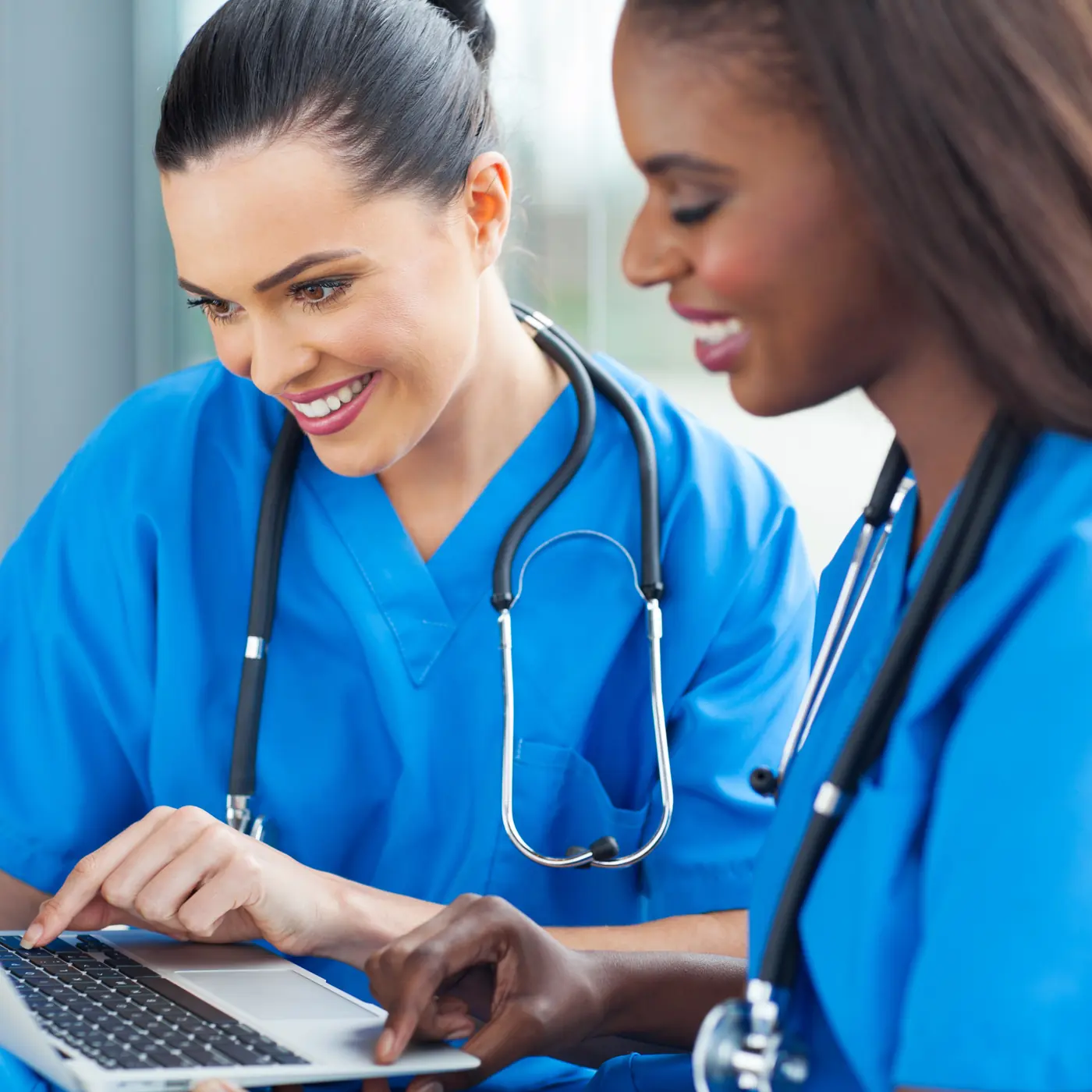 Two nurses reviewing information on a laptop
